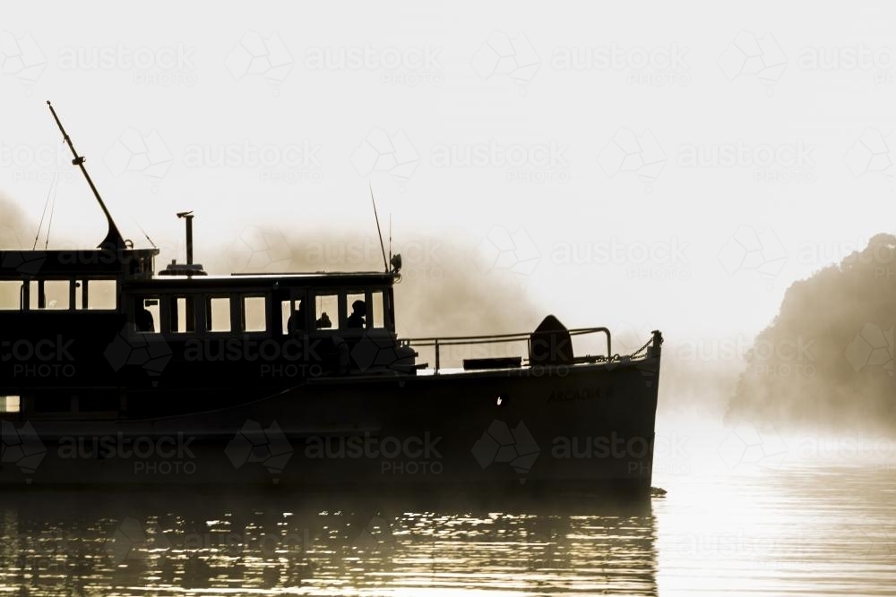 Silhouette of old wooden boat on the water - Australian Stock Image
