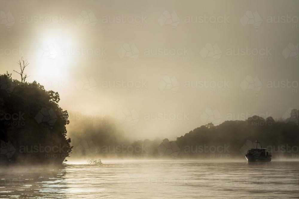 Silhouette of old wooden boat on the water in fog - Australian Stock Image