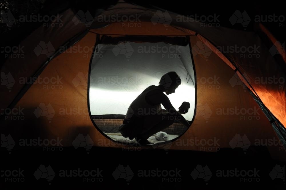 Silhouette of person in a tent - Australian Stock Image