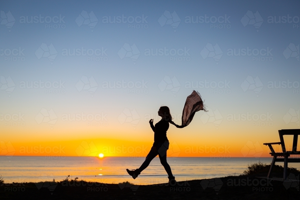 Silhouette of person striding out with scarf flowing behind - Australian Stock Image