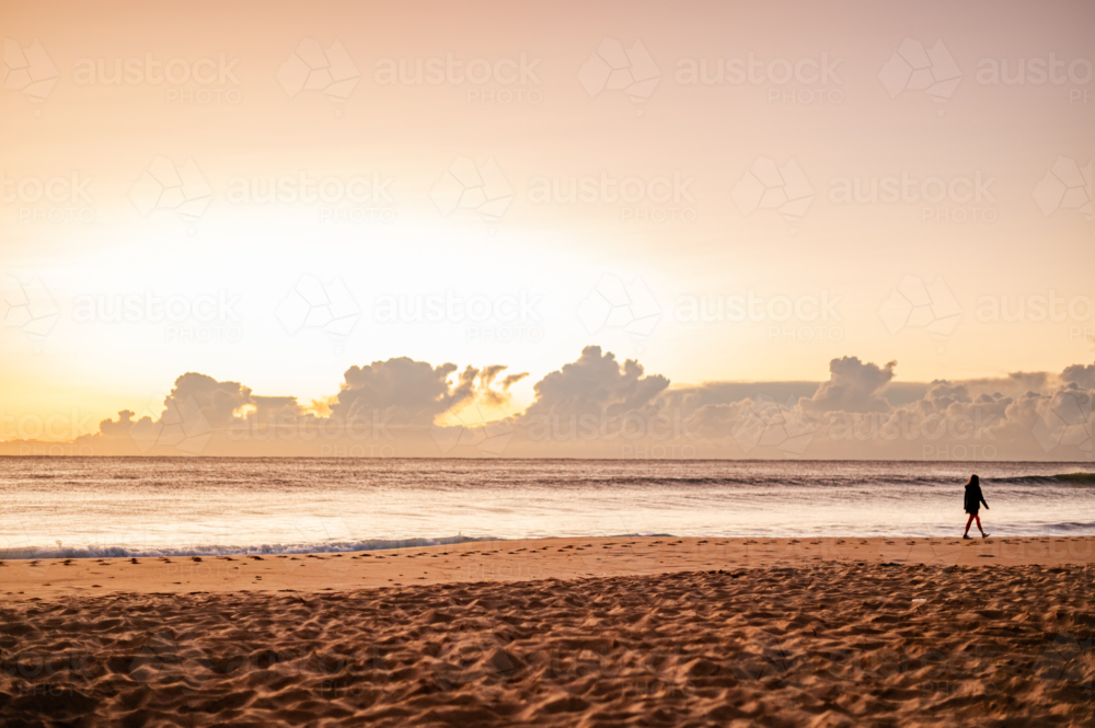 Silhouette of Person Walking on Beach at Sunset - Australian Stock Image