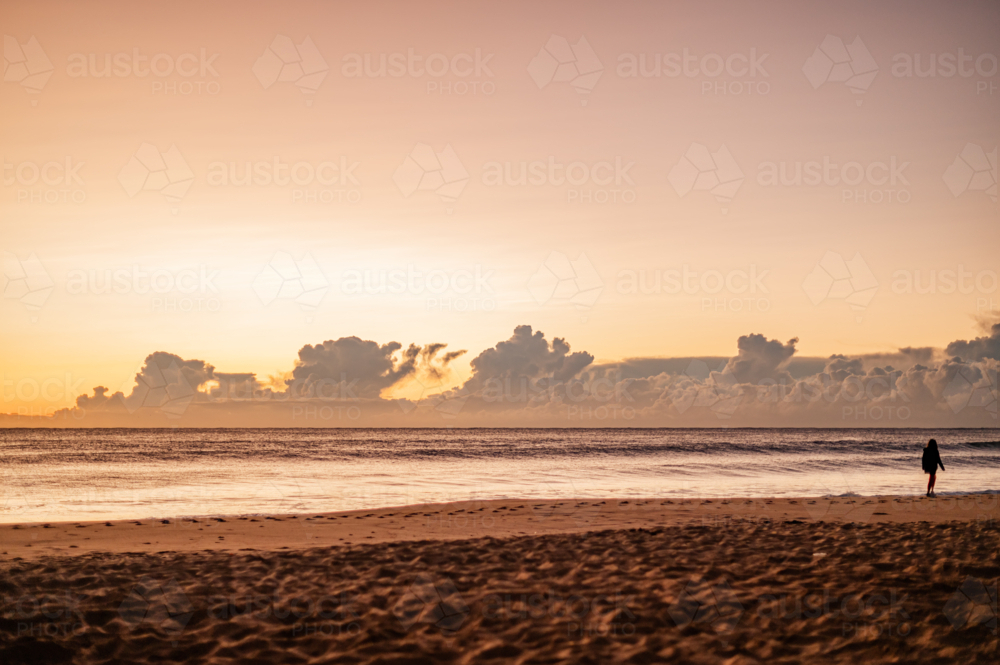 Silhouette of Person Walking on Beach at Sunset - Australian Stock Image