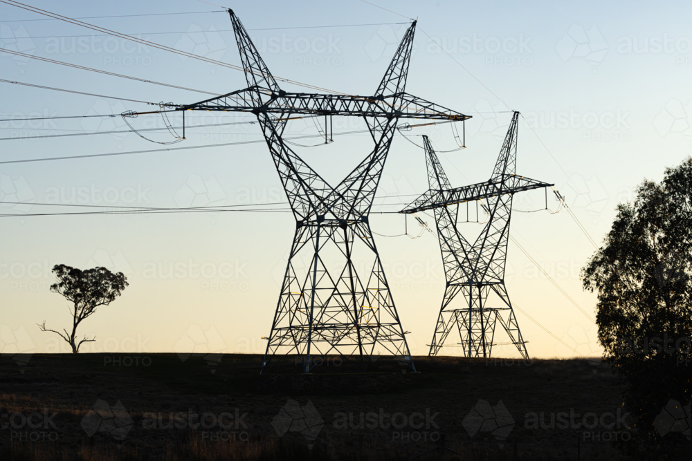 Silhouette of power lines and power poles with high voltage electricity at sunset - Australian Stock Image