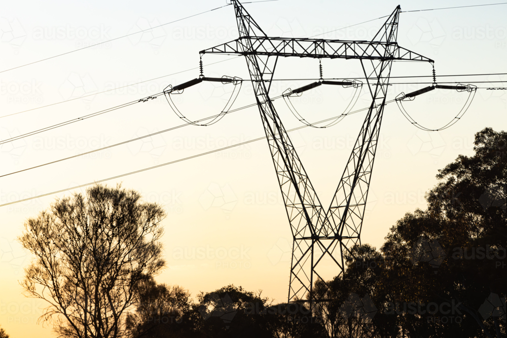 Silhouette of power lines and power poles with high voltage electricity at sunset - Australian Stock Image