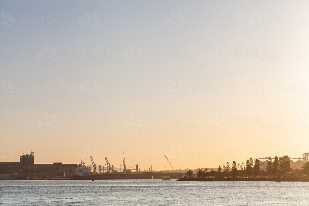 silhouette of ships in Newcastle port on the hunter river over water in evening light - Australian Stock Image