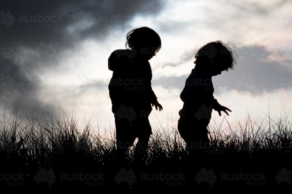 Silhouette of Toddlers Exploring in Dune Vegetation at Sunset - Australian Stock Image