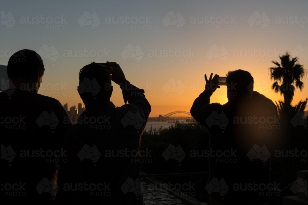 silhouette of tourists taking photos of Sydney harbour at sunset - Australian Stock Image