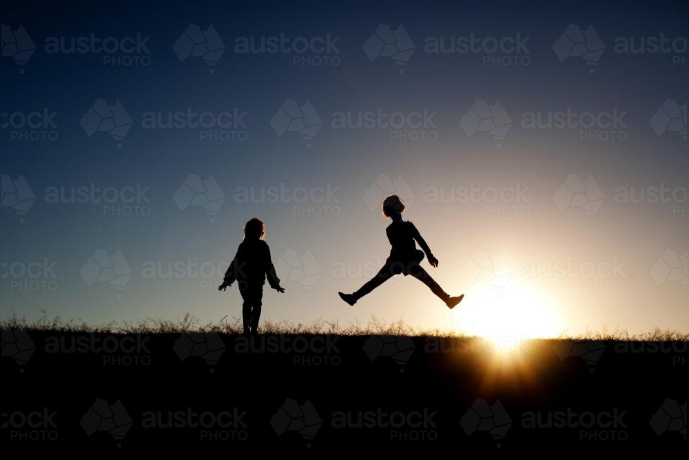 Silhouette of two girls at sunset - Australian Stock Image