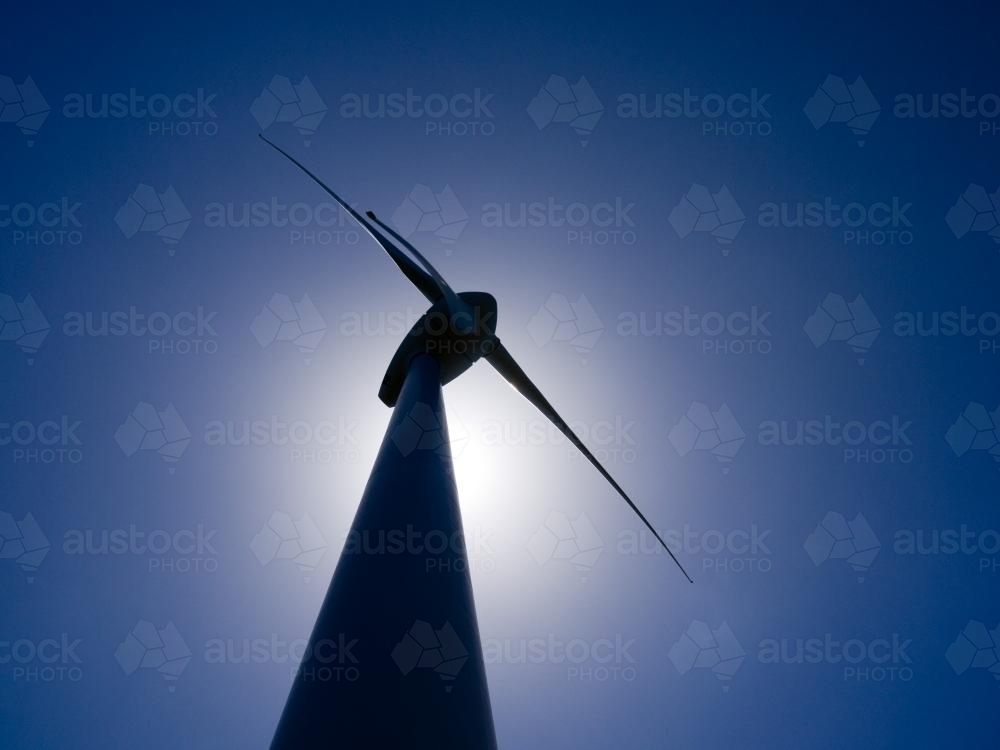 Silhouette of wind turbine against blue sky - Australian Stock Image