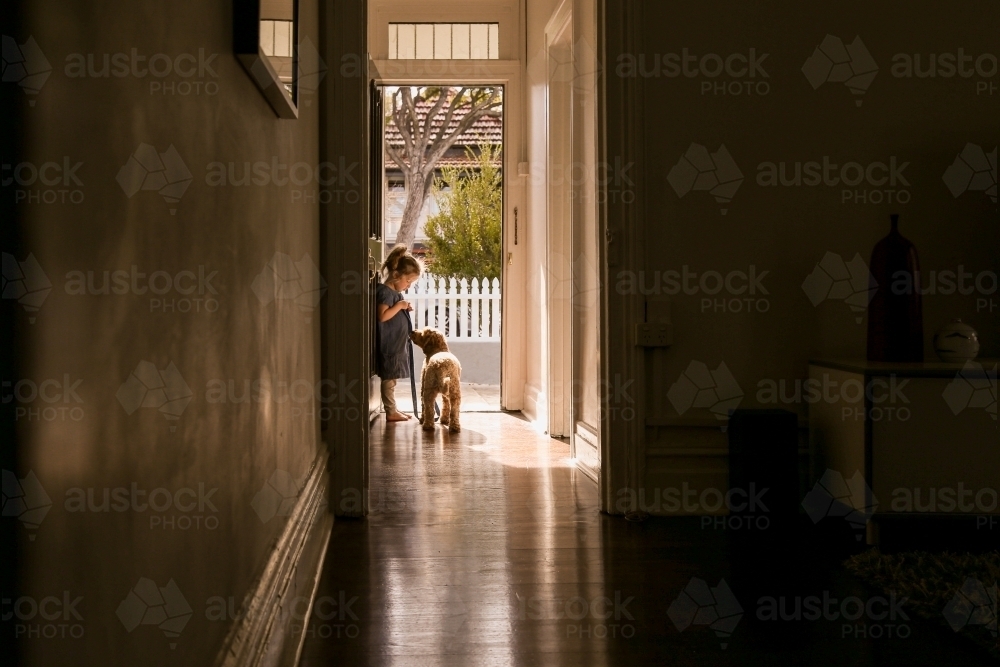 silhouette shot of a little girl with a dog on a leash in the corridor - Australian Stock Image