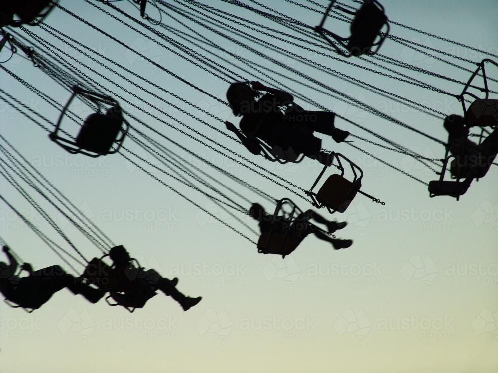 Silhouetted people in the air on a big Merry-Go-Round - Australian Stock Image
