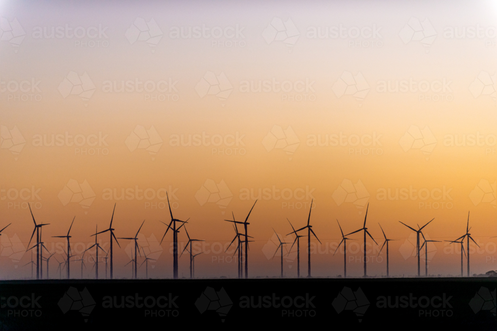 Silhouetted wind turbines at sunrise on a rural wind farm - Australian Stock Image
