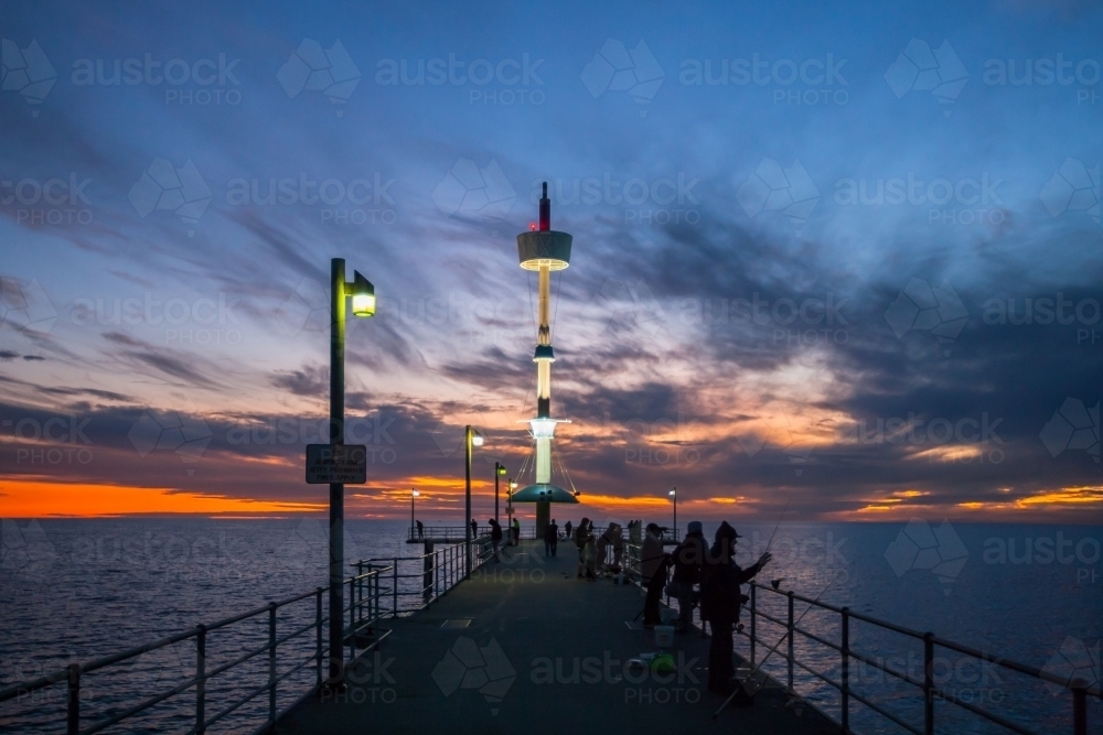 Silhouettes of people on a city pier at dusk - Australian Stock Image