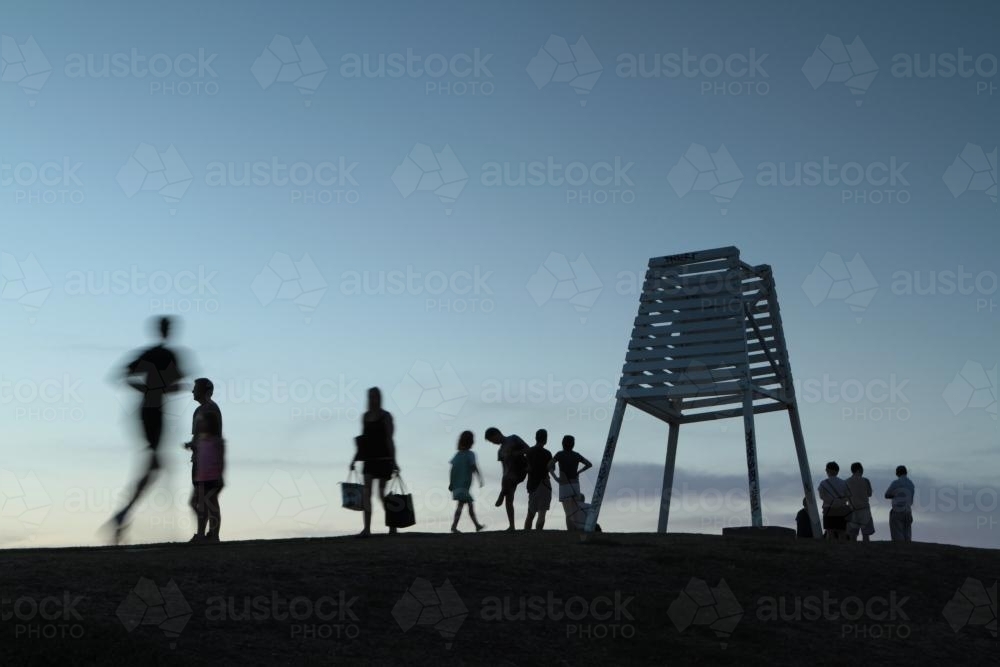 Silhouettes of people on a hilltop at dusk - Australian Stock Image