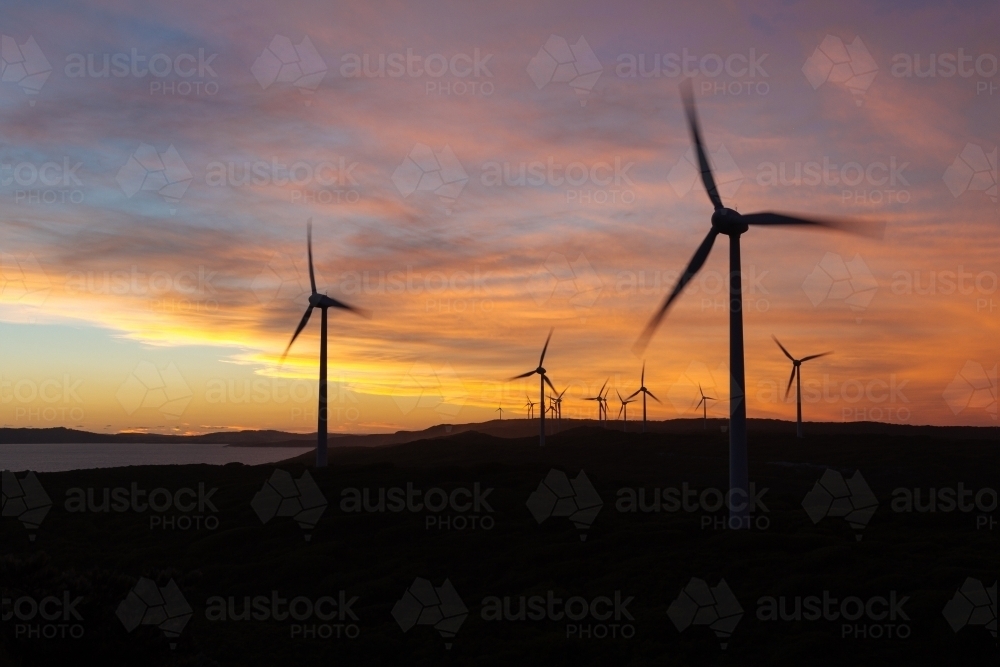 Silhouettes of wind turbines against a sunset lit sky - Australian Stock Image