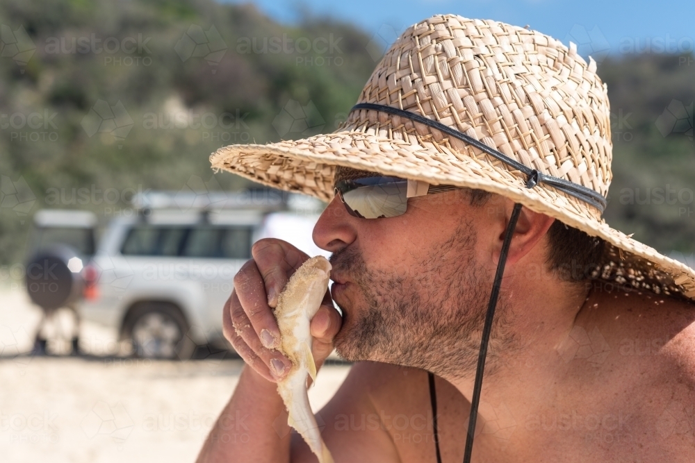 silly man kissing a fish before throwing it back - Australian Stock Image