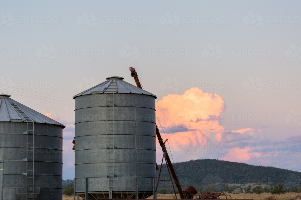 Silo on farm with cloud billowing behind and copy space in dusk sky - Australian Stock Image