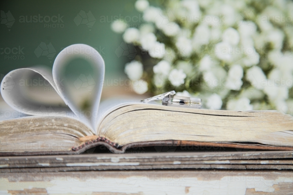 Silver bride and grooms wedding rings laid on the bible shaped in a heart - Australian Stock Image