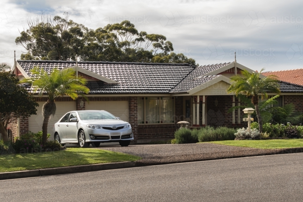 Silver car parked in suburban residential driveway - Australian Stock Image