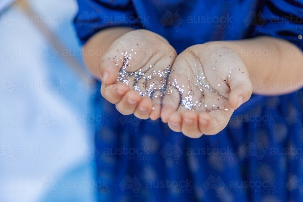 Silver glitter sparkles on childs hands - Australian Stock Image