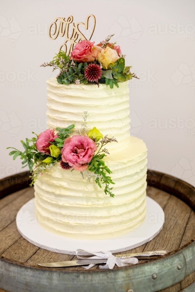 simple two tiered wedding cake with fresh flowers - Australian Stock Image