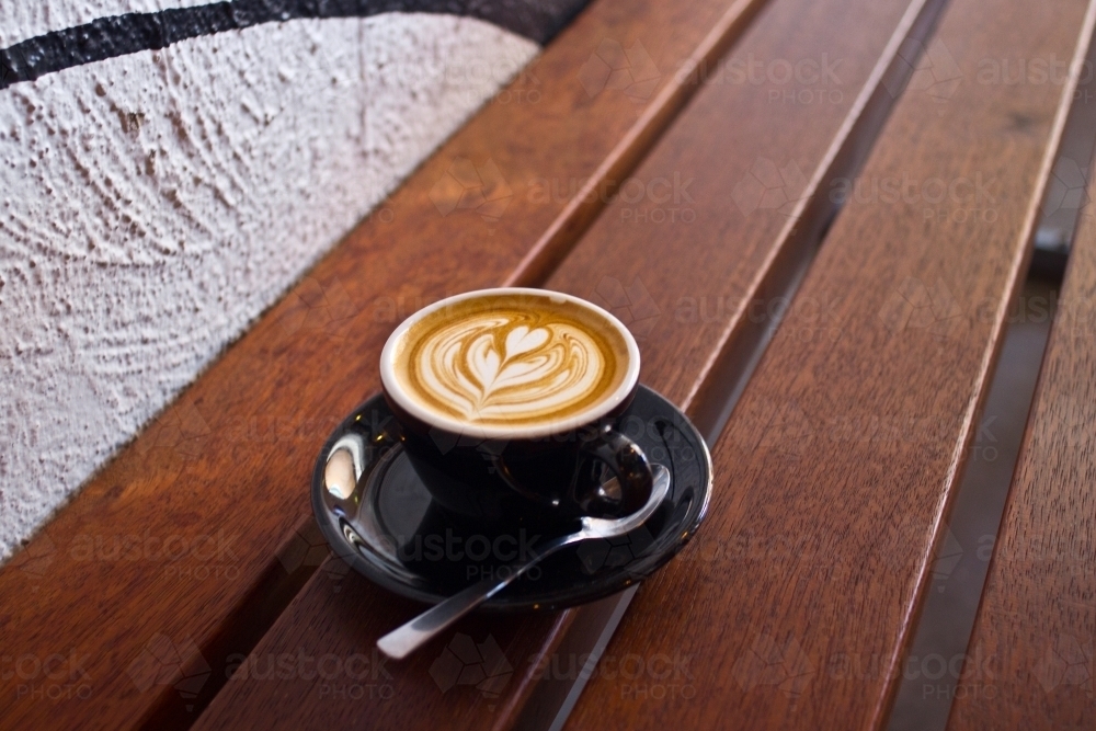 Single flat white coffee sitting on a wooden table - Australian Stock Image