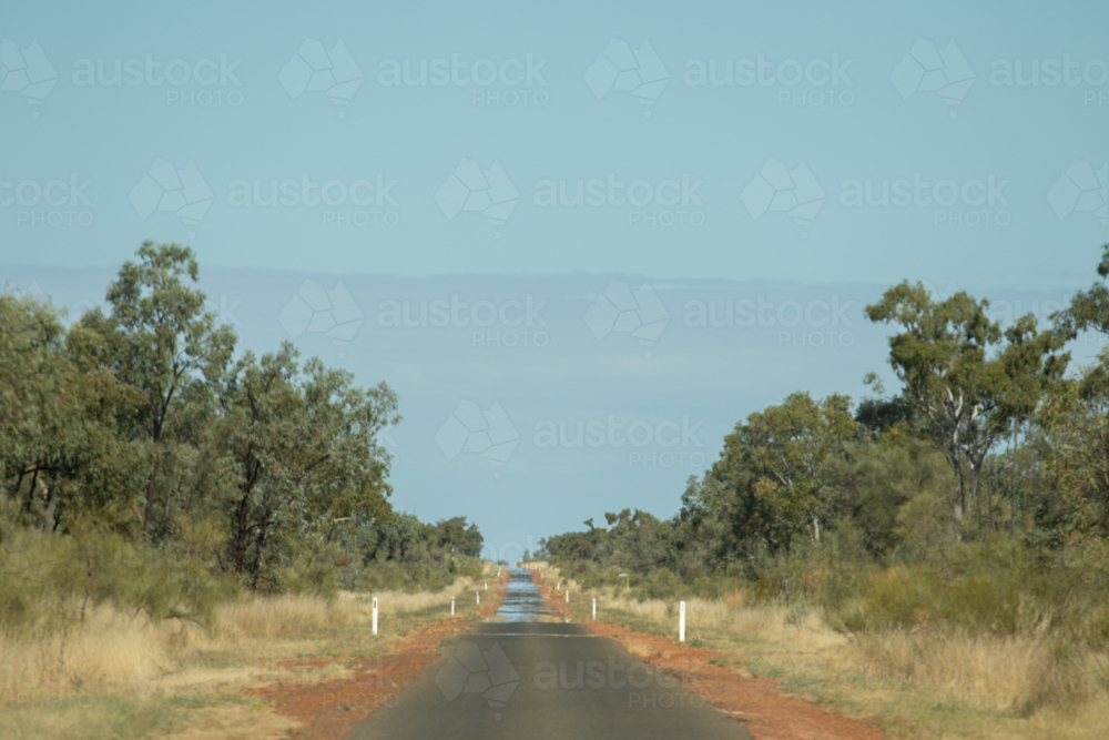 Single lane bitumen road in the outback, with mirage ahead - Australian Stock Image