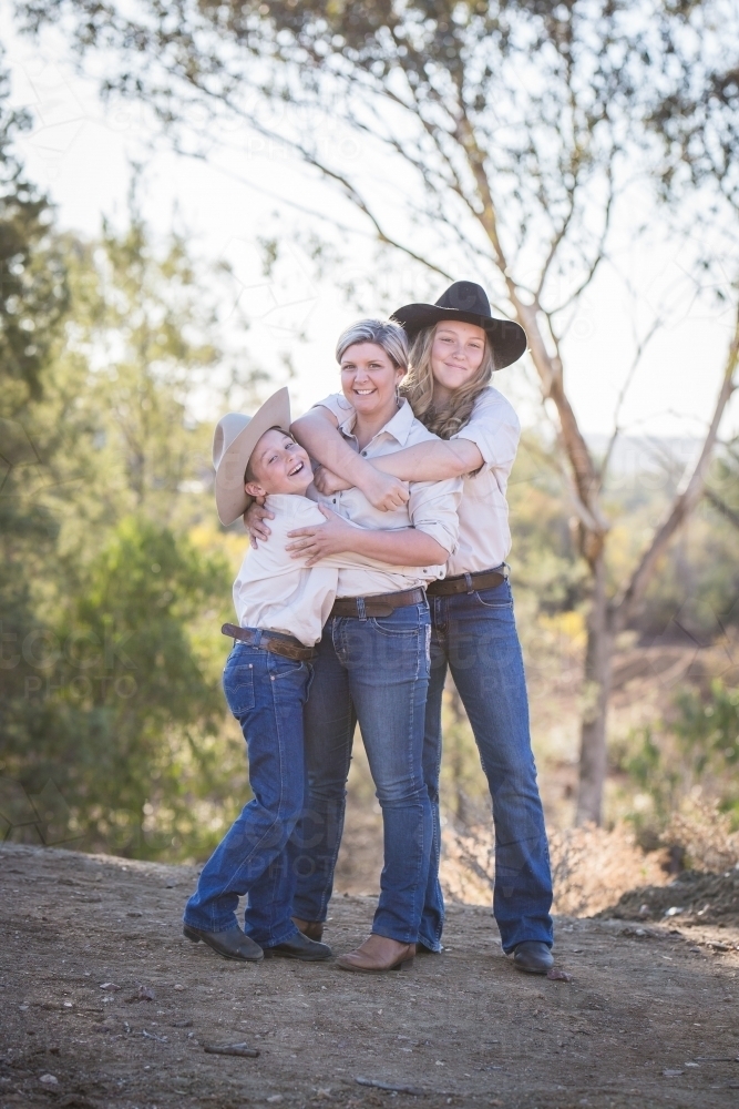 Single mother being hugged by children on family farm in drought - Australian Stock Image