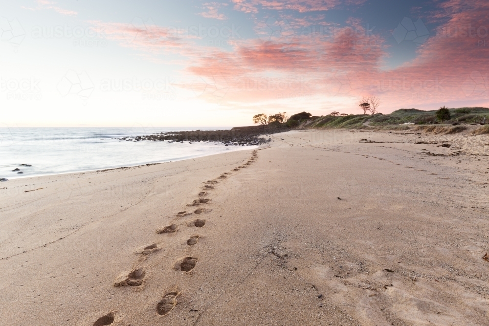 Single set of footprints along the beach in the early morning - Australian Stock Image