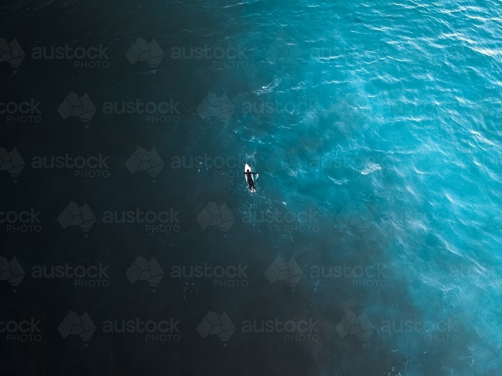 Single surfer paddling in the ocean - Australian Stock Image
