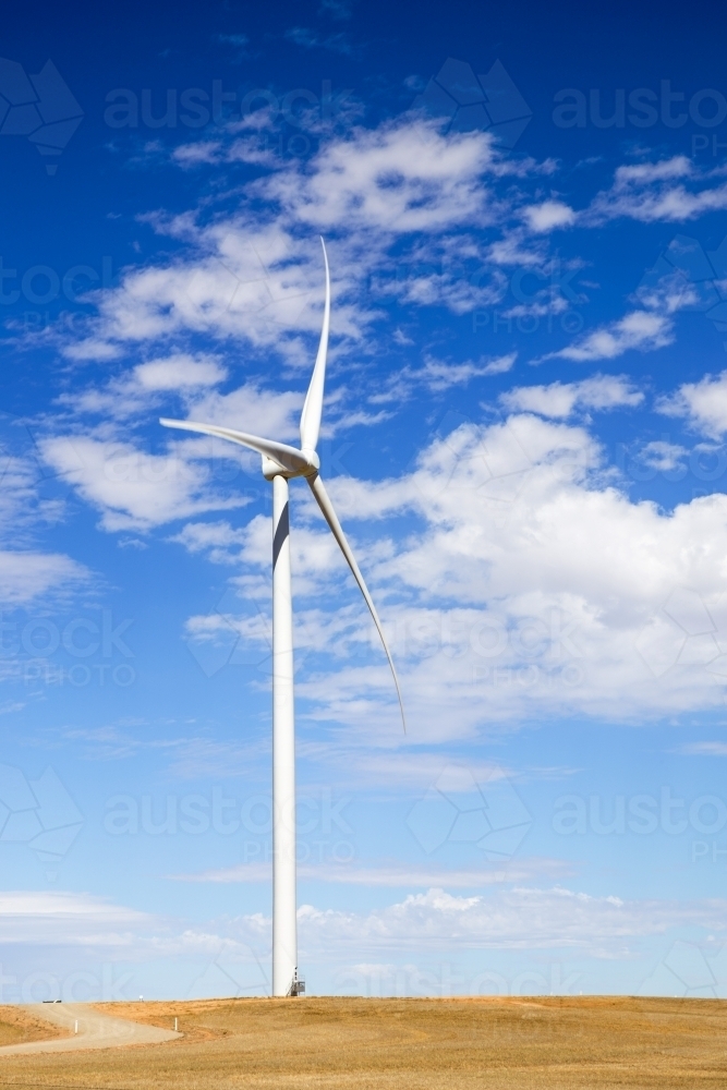 Single wind turbine against blue sky with white clouds - Australian Stock Image