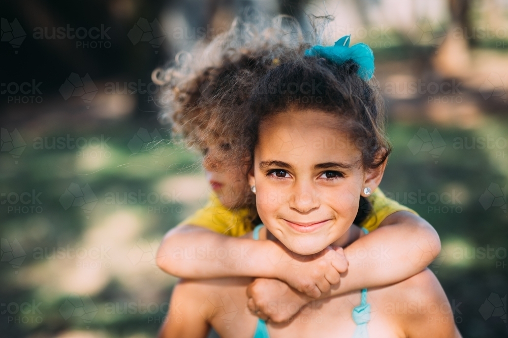 Sister carrying brother on her back - Australian Stock Image