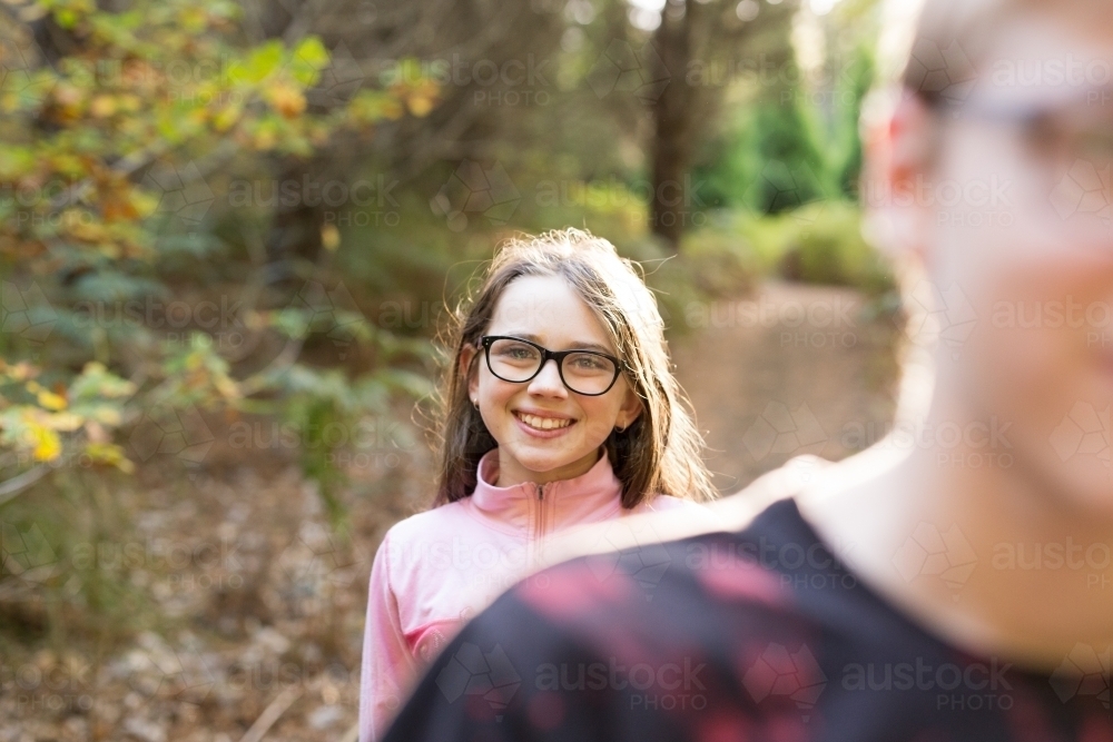 Sister standing behind brother in forest - Australian Stock Image