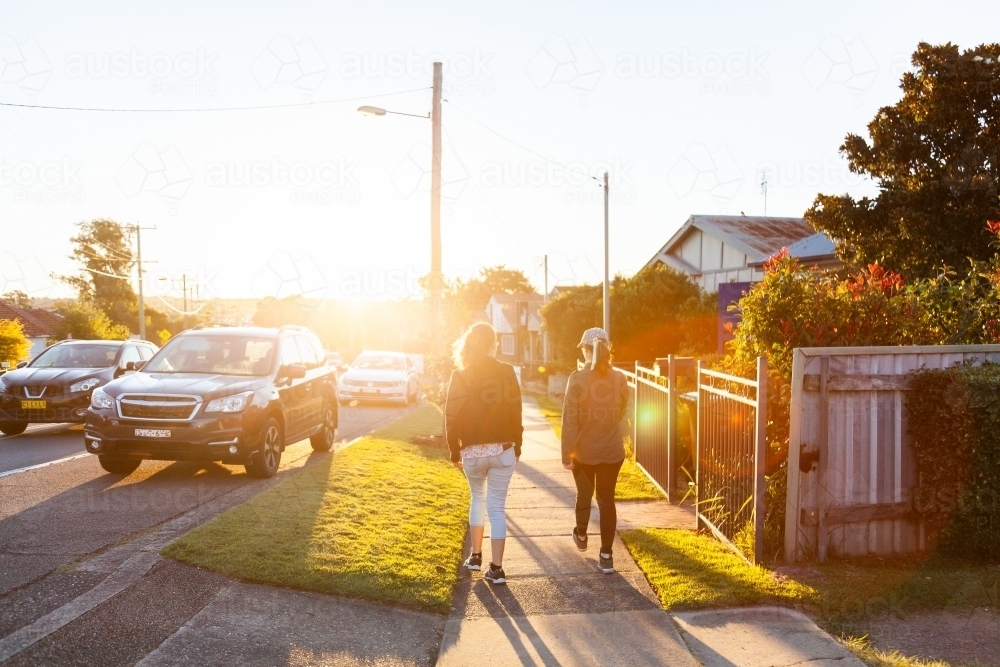 Sisters go on an evening walk down sunlit street in Newcastle - Australian Stock Image