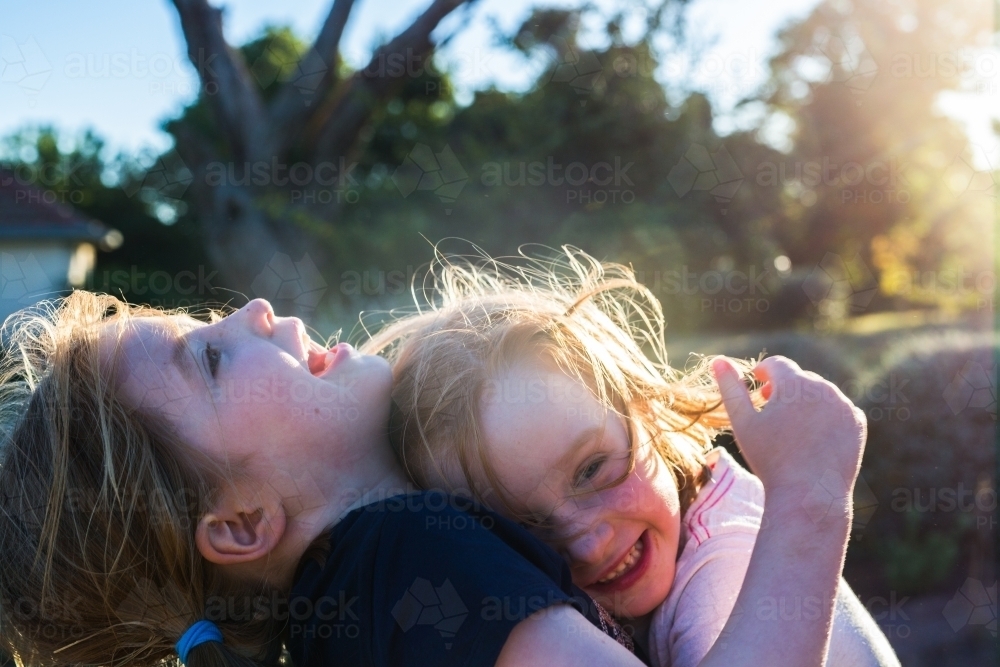 Sisters hugging in the sunshine - Australian Stock Image