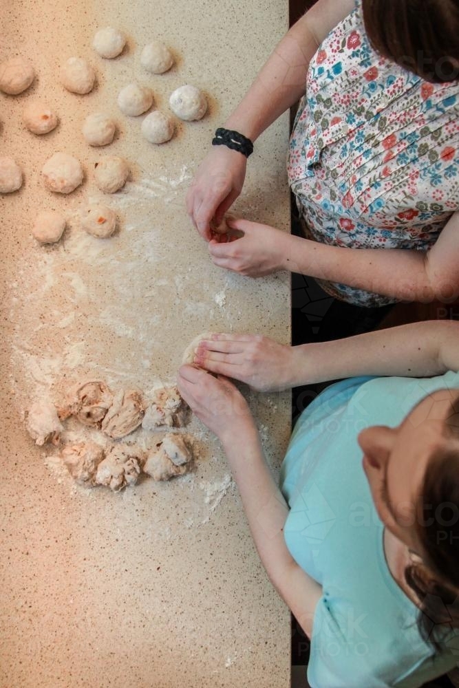 Sisters kneading hot cross bun dough in the kitchen - Australian Stock Image