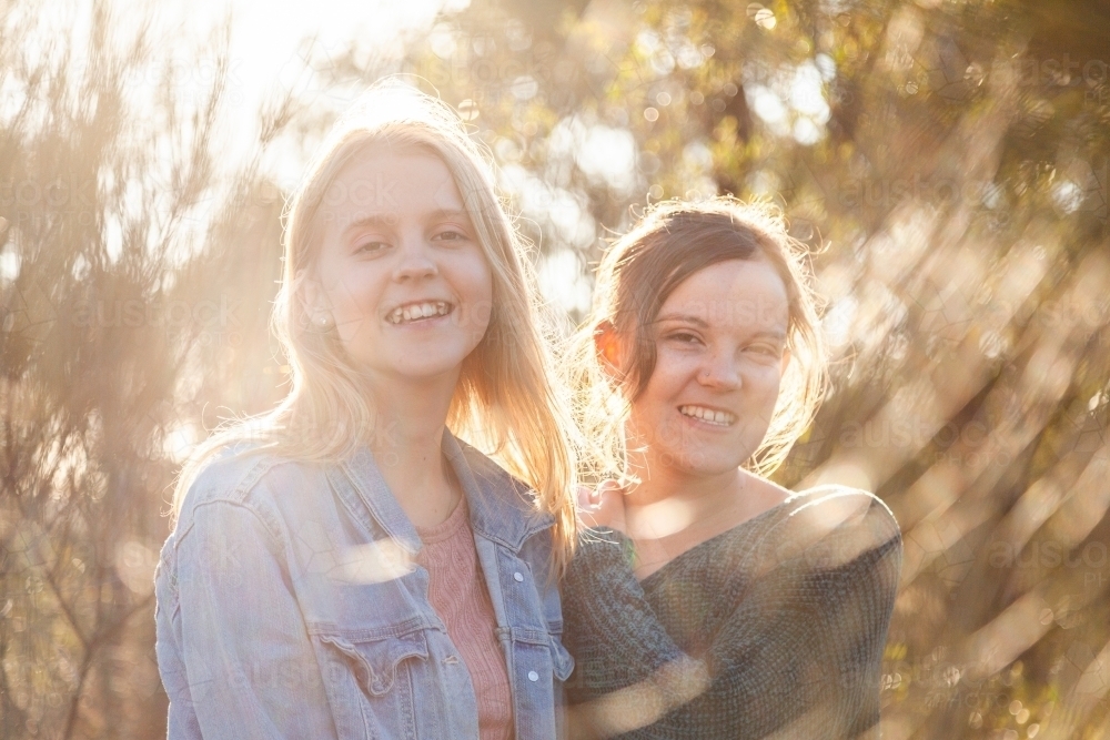 Sisters laughing together and giving one another a hug - Australian Stock Image