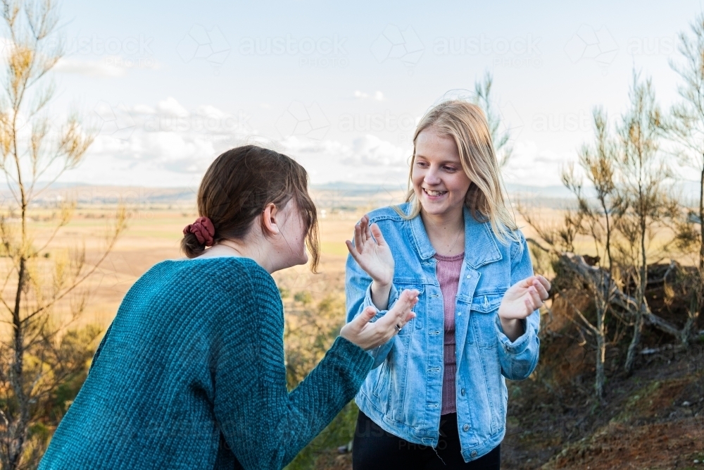 Sisters playing a clapping game laughing together - Australian Stock Image