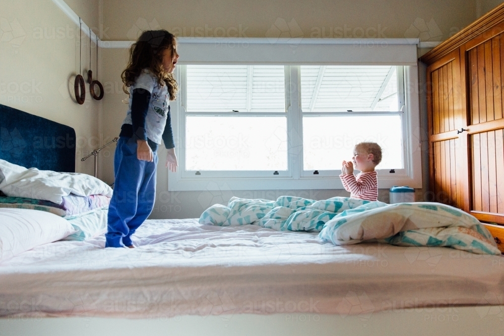 Sisters playing on mum's bed - Australian Stock Image