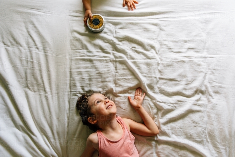 Sisters playing together on parents bed - Australian Stock Image