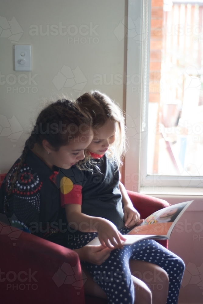 Sisters reading together - Australian Stock Image