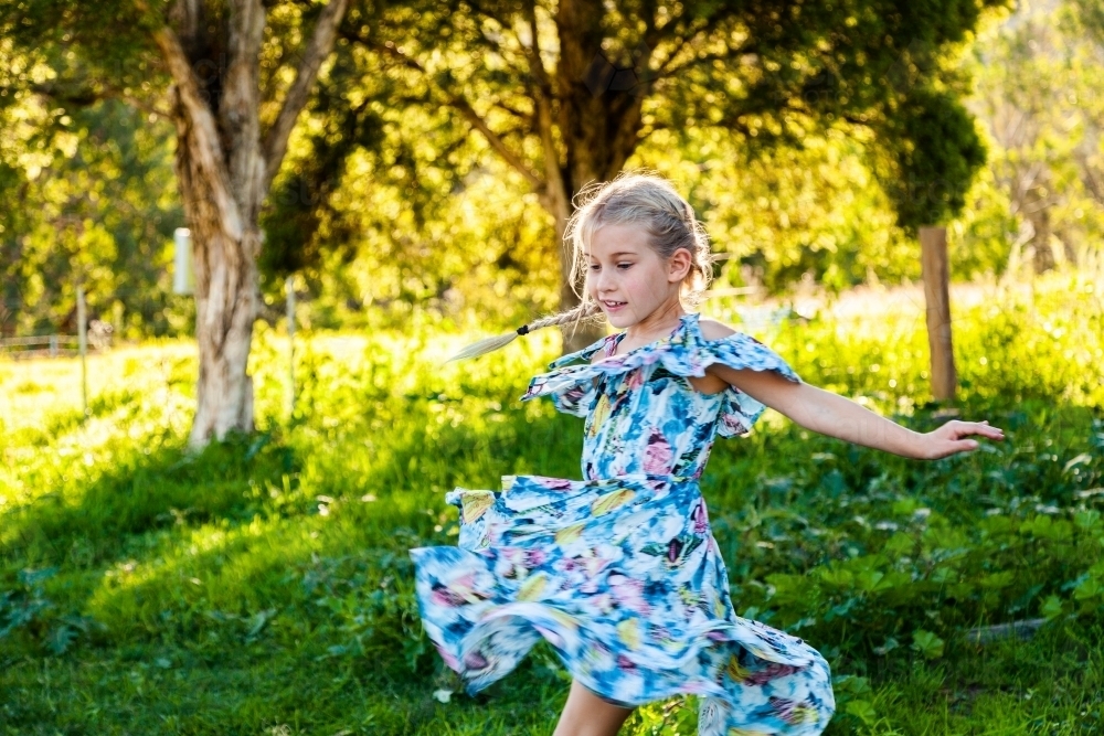 Six year old girl twirling outside in blue dress - Australian Stock Image