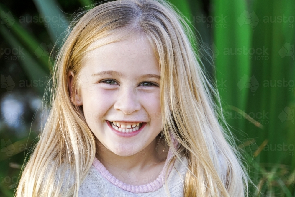 Six year old girl with blonde hair and cheeky smile - Australian Stock Image
