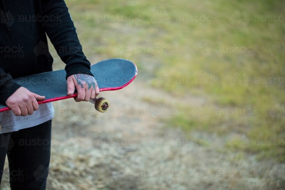Skateboard being held with tattooed hands : Austockphoto Skateboard being held with tattooed hands - Australian Stock Image