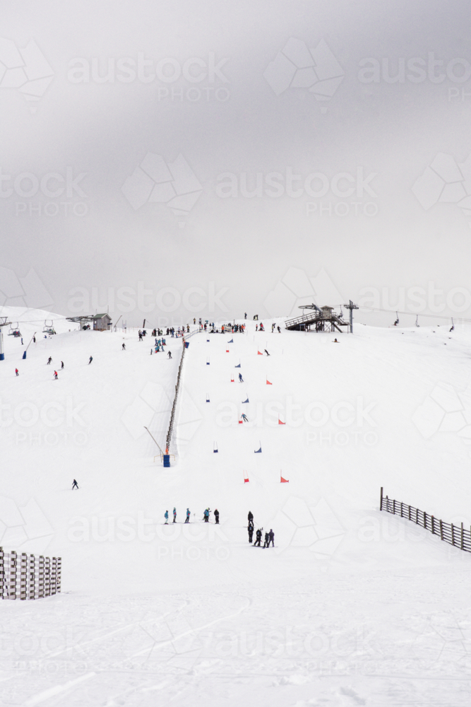 Ski lift with ski race course in distance on snowy mountain - Australian Stock Image