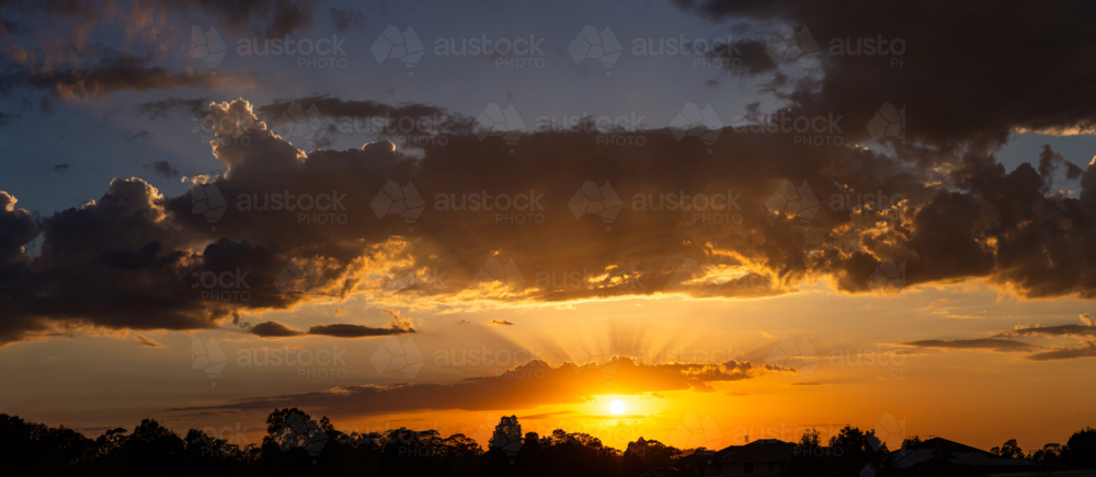Skyscape of sun with golden rays of light from behind clouds at sunrise - Australian Stock Image