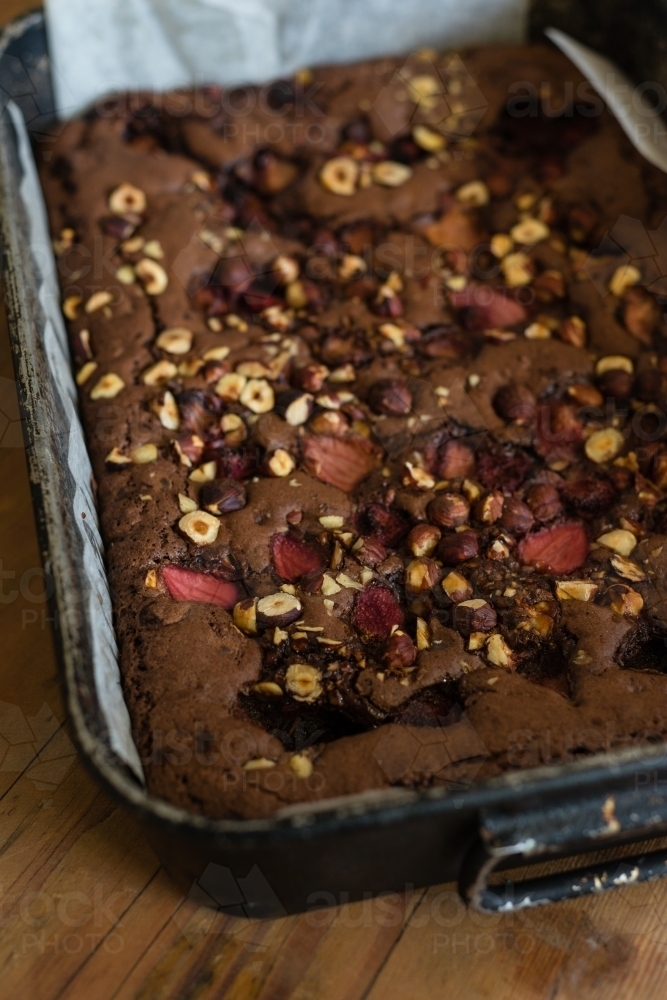 slab of freshly baked chocolate brownie with hazelnuts and strawberries - Australian Stock Image