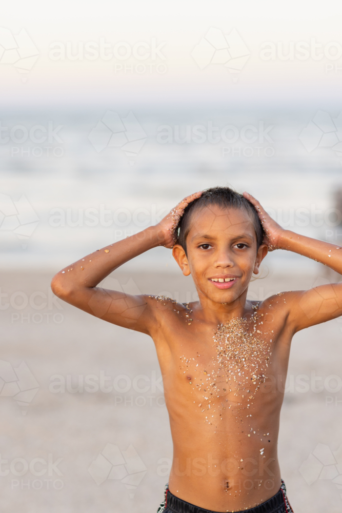 slim young boy with coarse sand on skin on the beach - Australian Stock Image
