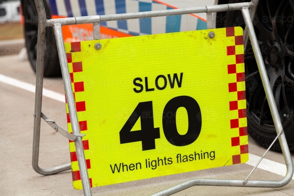 Slow 40 when lights flashing sign beside police car - Australian Stock Image