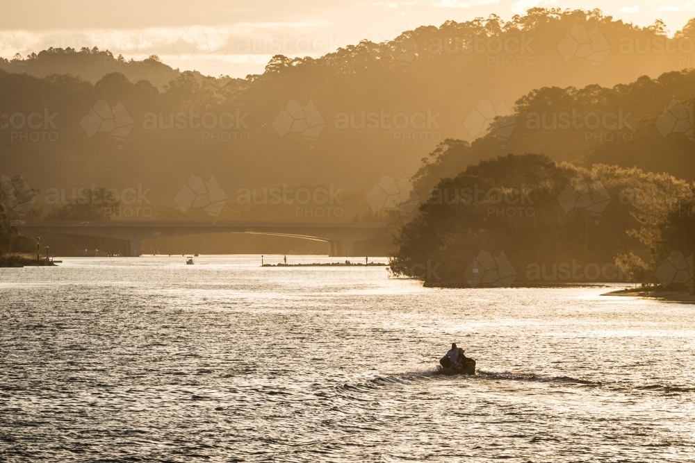 Small boat on a river at sunset - Australian Stock Image